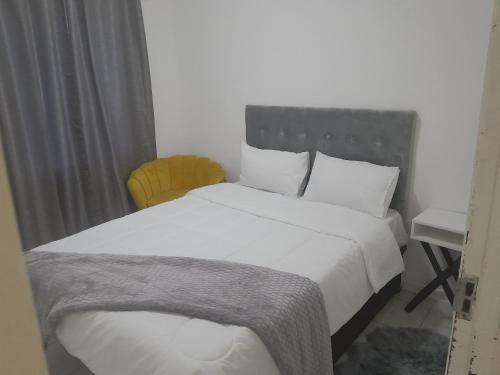 een slaapkamer met een wit bed en een bureau bij The Nexus Suites in Gaborone