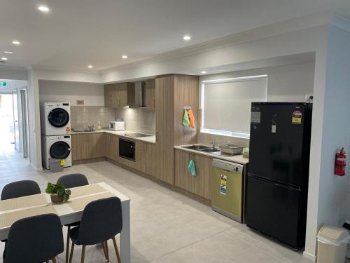 a kitchen with a black refrigerator and a table and chairs at Southeastern Retreat in Clyde North