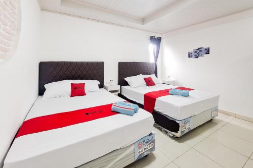 a bedroom with two beds with red and white sheets at RedDoorz at Hotel Lavender Kertajati in Gadel