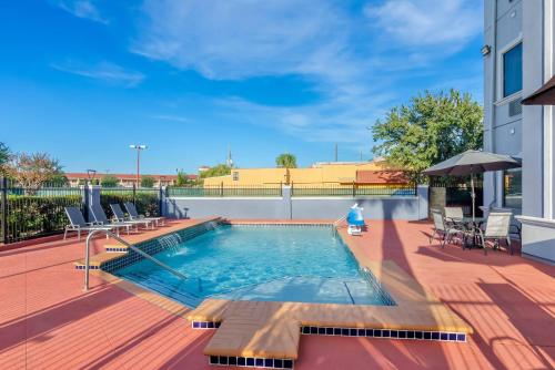a swimming pool on a deck with chairs and a building at Quality Suites Houston NW Cy-Fair in Houston