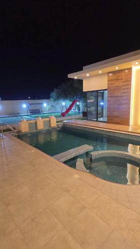 una piscina di fronte a un edificio di notte di Sand Paradise a Badīyah