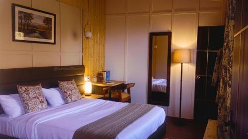 a bedroom with a bed and a desk with a lamp at Bhimtal Lakeview Cottage in Bhīm Tāl