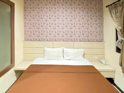 a bedroom with a bed and a pink wall at Lily Guest House Syariah RedPartner in Bunul