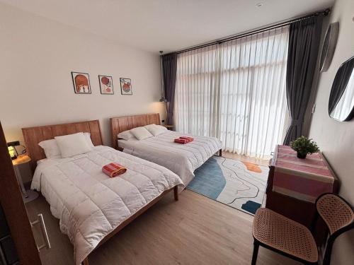 een slaapkamer met twee bedden, een tafel en een raam bij Villanarachaam in Cha Am