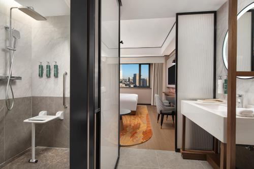 ein Badezimmer mit Dusche und Waschbecken in der Unterkunft Hilton Garden Inn Tianjin Five Great Avenues in Tianjin