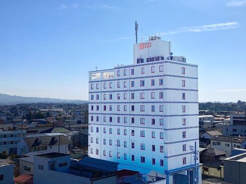 a white building with a red sign on top of it at KOKO STAY Sukagawa- formerly Hotel Wing International Sukagawa in Sukagawa