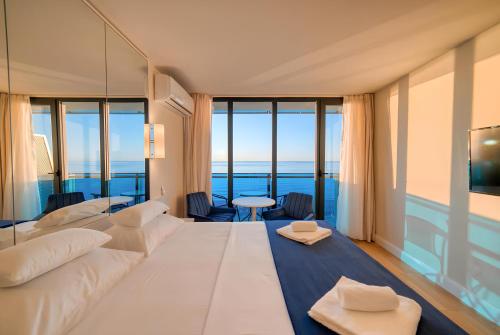 un salon avec un grand canapé blanc et de grandes fenêtres dans l'établissement Panorama Batumi Towers, à Batoumi