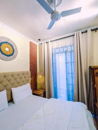 a bedroom with a bed and a ceiling fan at Kali Hideaway Experience Arusha in Arusha