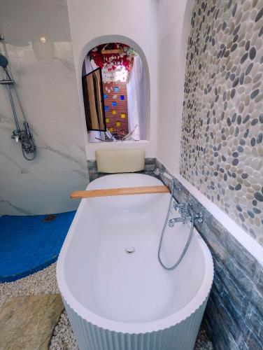 a white tub in a bathroom with a mirror at Kali Hideaway Experience Arusha in Arusha