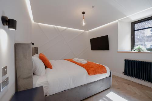 a white bedroom with a bed and a flat screen tv at Old Kirk Apartment in Oban