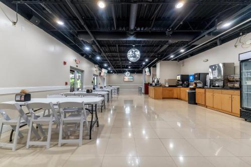 a restaurant with white tables and chairs and a kitchen at Rodeway Inn & Suites Fort Lauderdale Airport & Cruise Port in Fort Lauderdale