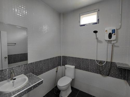 een badkamer met een douche, een toilet en een wastafel bij Saint Jira Hotel in Chum Phae