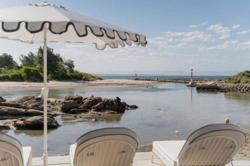 a beach with two chairs and an umbrella and water at Nomaya Waterfront Getaway in Currarong
