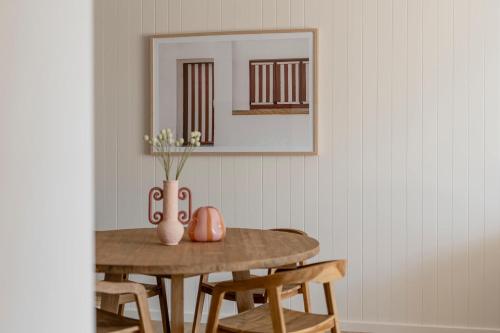 a dining room table with a vase with flowers on it at Nomaya Waterfront Getaway in Currarong