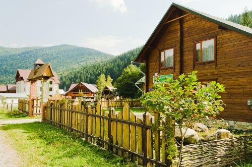a wooden fence in front of a wooden house at Kryvorizka Palanka in Mykulychyn