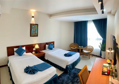 een hotelkamer met twee bedden en een tafel bij The Coast Hotel Vung Tau in Vung Tau