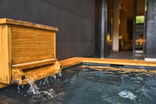 a pool of water with a wooden water fountain at Hakone Hibarino hot spring hotel in Hakone