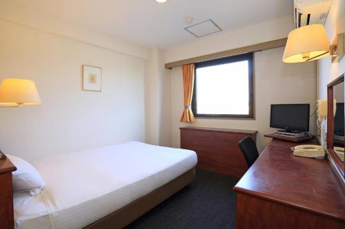 a hotel room with a bed and a desk with a computer at Smile Hotel Koriyama in Koriyama