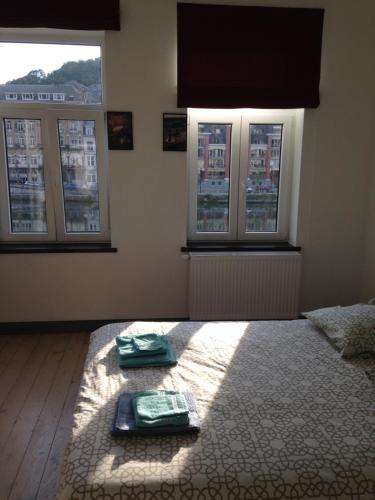 a bedroom with three windows and a bed with towels at Les Voisins De Mr Sax in Dinant