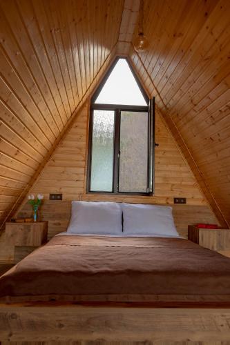 a bedroom with a large bed with a window at Aurarest - აურარესთ in Makho