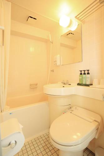 a bathroom with a toilet and a sink and a tub at Smile Hotel Koriyama in Koriyama