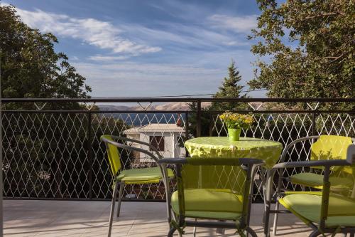 a balcony with green chairs and a table with a vase on it at Apartman Davorka in Karlobag