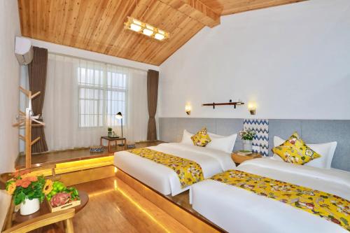 two beds in a hotel room with wooden ceilings at 大理六悦客栈Dali Liuyue Inn in Dali