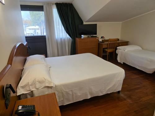 een hotelkamer met twee bedden en een bureau bij Hotel Dimora Adriana in Tivoli