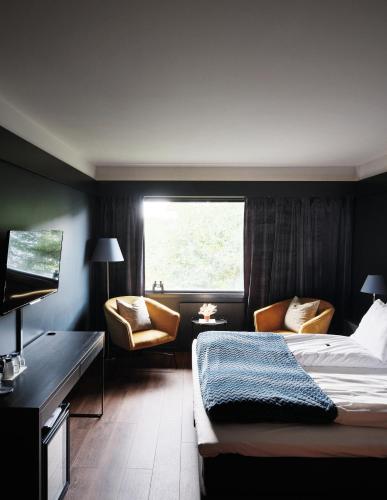 a hotel room with a bed and chairs and a window at Oscarsborg Castle Hotel & Resort in Drøbak
