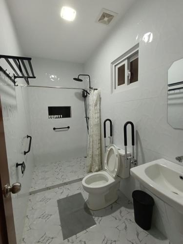 a white bathroom with a toilet and a sink at Pip.Avenue Beach House in San Narciso
