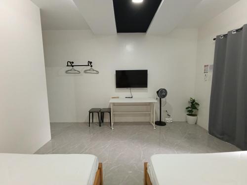 Dieses weiße Zimmer verfügt über einen TV und einen Schreibtisch mit einem Computer. in der Unterkunft Pip.Avenue Beach House in San Narciso