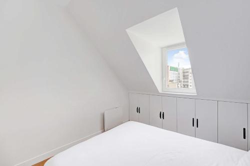 een witte kamer met een bed en een raam bij Comfortable and modern 2P studio - 16th Paris in Parijs