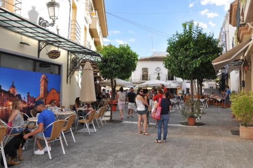 a group of people sitting at tables in a street at Casa de las Remigias in Estepona