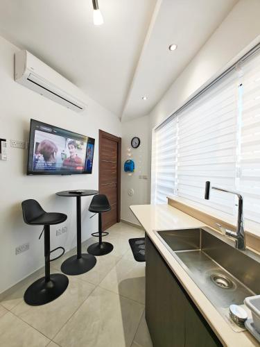Eine Küche mit zwei Barhockern und einem Fernseher an der Wand. in der Unterkunft Valley View 4 in Luqa