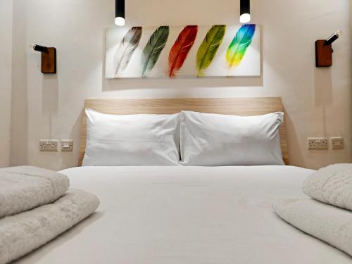 ein Schlafzimmer mit einem weißen Bett und bunten Federn an der Wand in der Unterkunft Valley View 4 in Luqa