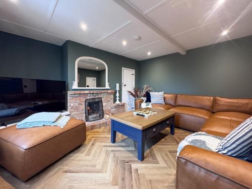 ein Wohnzimmer mit Ledermöbeln und Kamin in der Unterkunft Hill House - Uk49727 in Oxborough