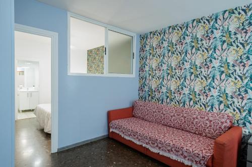 een woonkamer met een rode bank en een muur bij Center Sevilla Magdalena Premium in Sevilla