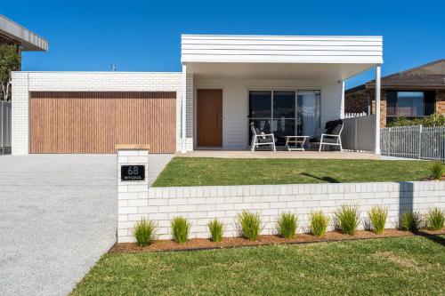 a white house with a fence and a yard at Myuna - beachfront pet-friendly coastal escape in Vincentia
