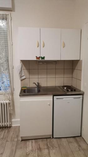 une cuisine avec des armoires blanches et un évier dans l'établissement Studio mignon en plein centre de Vichy, à La Celle-sous-Gouzon