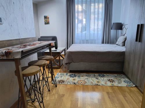 a small room with a bed and a table and stools at Apartman Iva Brzeće-Kopaonik in Brzeće