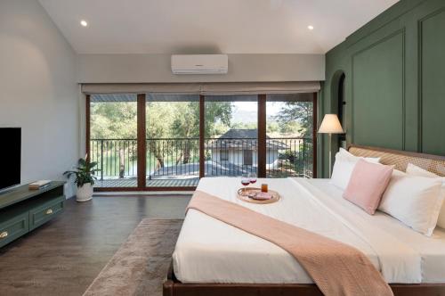 a bedroom with a large bed and a balcony at SaffronStays La Mia Casa in Jāmb