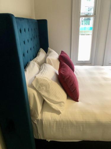 a bed with two red pillows and a blue headboard at 50 Green St Windsor in Melbourne