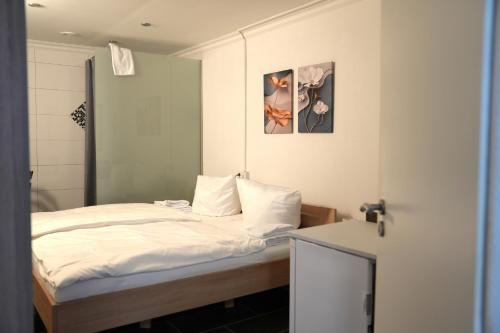 a small bedroom with a bed with white sheets at Hotel am Schürblick in Gronau