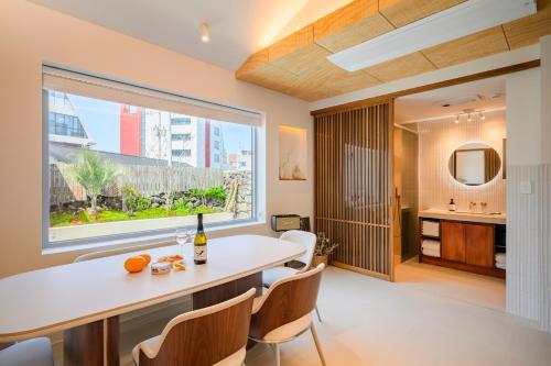 a dining room with a table and chairs and a large window at Hold in Hamdeok with Pool in Jeju