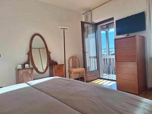 ein Schlafzimmer mit einem Bett, einem Spiegel und einem Fernseher in der Unterkunft Camera con vista in Calalzo