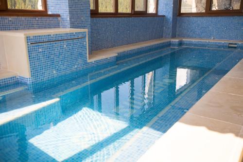 a large swimming pool with blue tiles on the floor at Pensiunea Sureanu in Tău Bistra