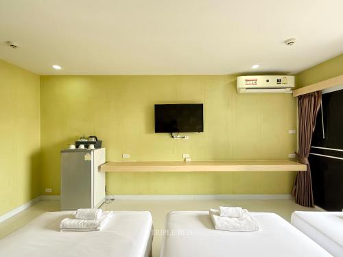 a room with two beds and a tv on the wall at Family Hotel Khon Kaen - แฟมิลี่ โฮเทล ขอนแก่น in Khon Kaen