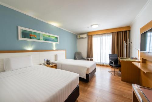 a hotel room with two beds and a desk at Maple Hotel in Bangkok
