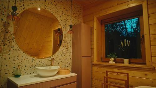 een badkamer met een wastafel, een spiegel en een raam bij Domek w sam las in Ochotnica Dolna
