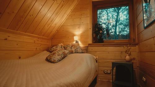 een slaapkamer met een bed in een houten hut bij Domek w sam las in Ochotnica Dolna